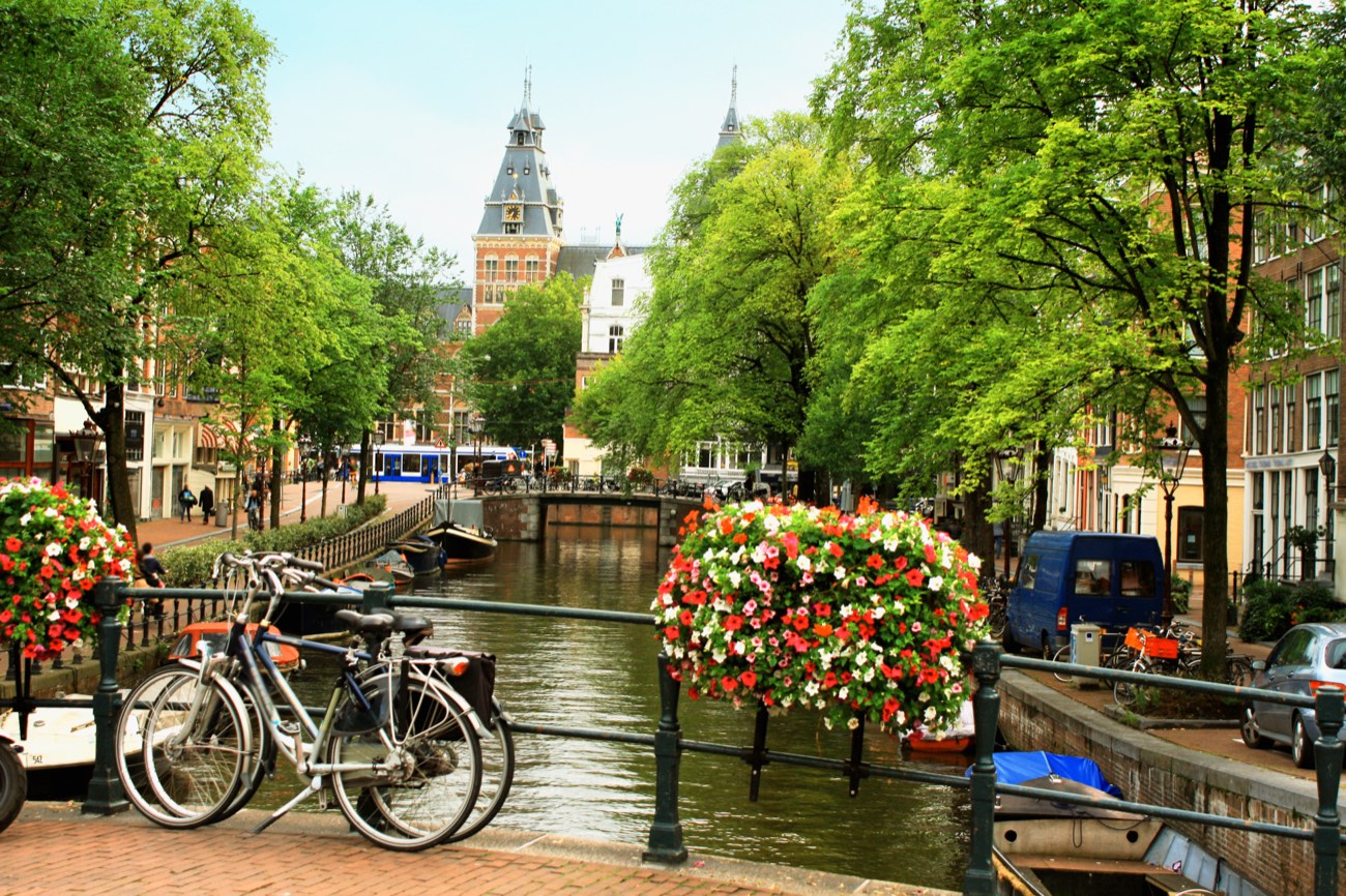 An Amsterdam canal near the Rijksmuseum, bicycles and flower baskets on the bridge