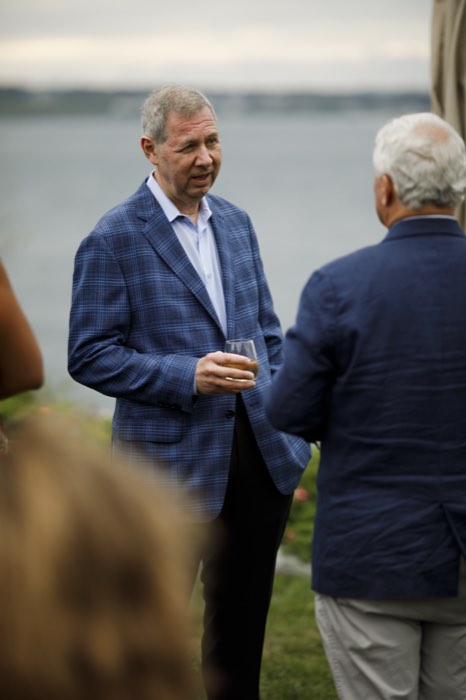 Two principals in conversation, the bay behind them.