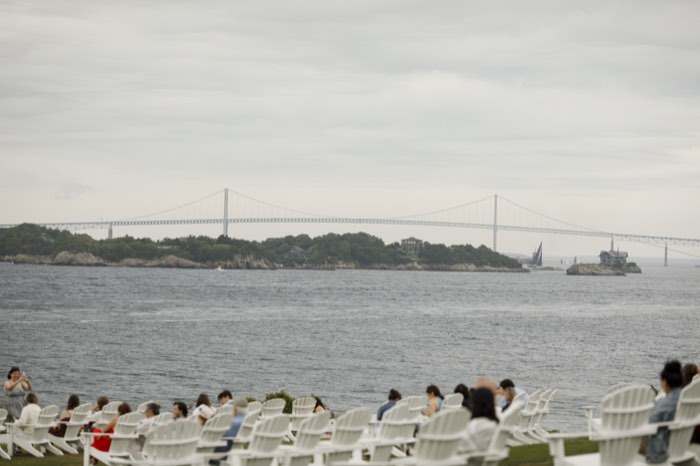 White chairs facing the bay, with the Newport Pell Bridge beyond.