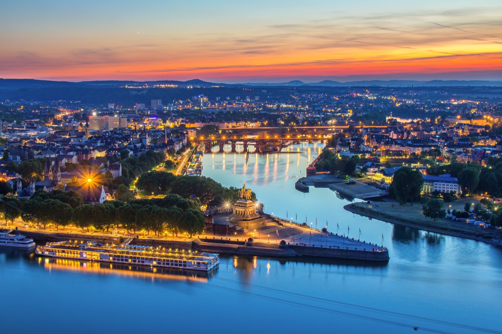 Koblenz at sunset, the Deutsches Eck monument and a river ship on the route of the Inaugural Voyage