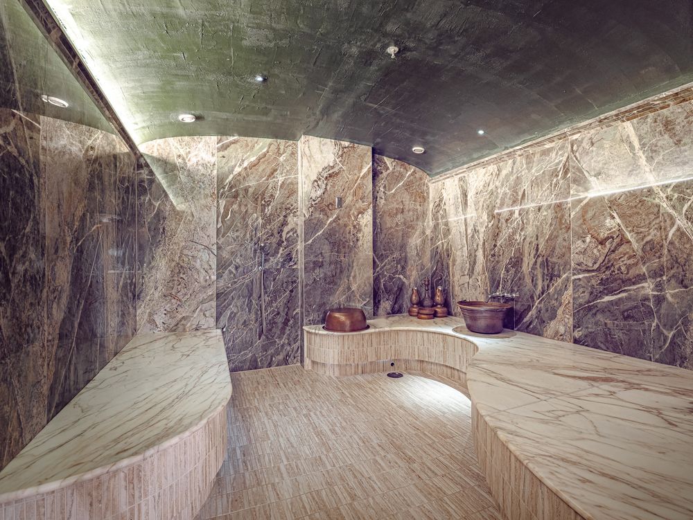 A marble-lined room with curved stone benches in the Spa at Seafire