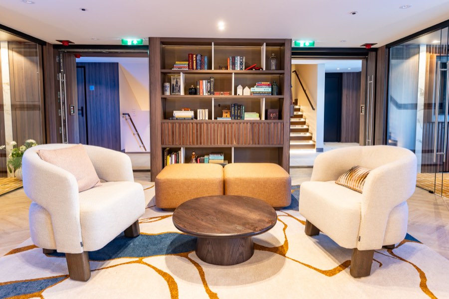 The Library lounge with armchairs and a bookshelf room divider